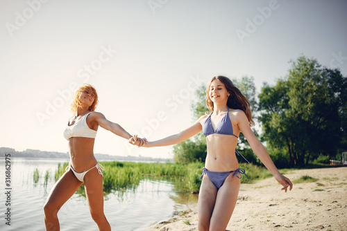 Family near a lake. Beautiful mother with cute daughter. Girls in a stylish swimsuits