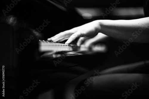 Grey scale shot of a the hands of a person playing the piano