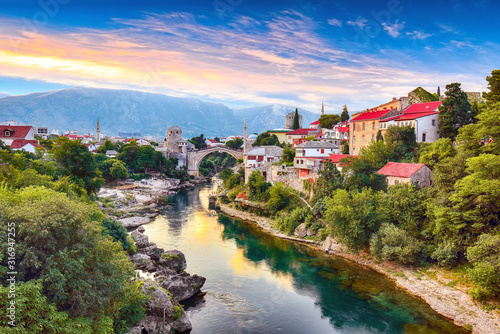 Fantastic Skyline of Mostar with the Mostar Bridge, houses and minarets, at sunset