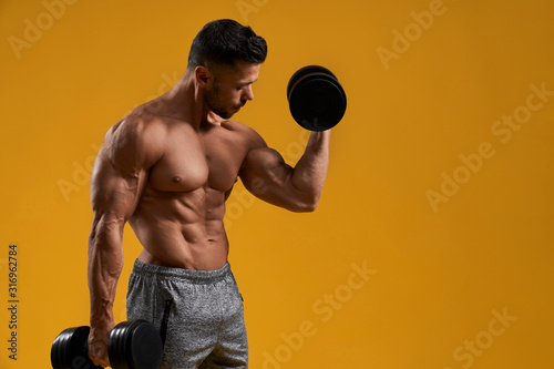 Athletic young man doing exercise for biceps
