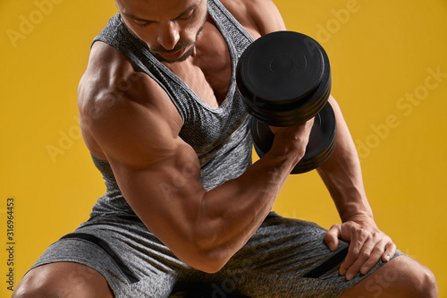 Muscular young gentleman pumping up biceps