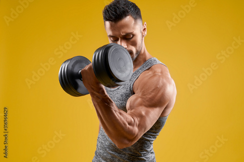 Handsome bodybuilder working out with dumbbell