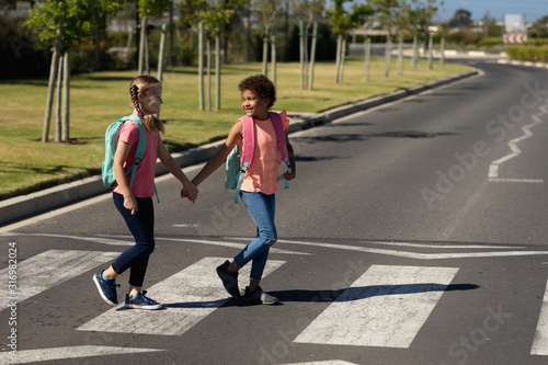Two schoolgirls crossing the road on a pedestrian crossing