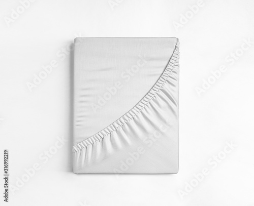 Flat sheet or bed cover folded. White fitted sheet isolated. White sheet with elastic band.