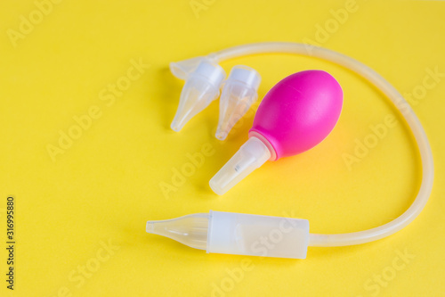 The concept of medicine and hygiene of the child. Children's nasal aspirator on a yellow background. Copyspace.