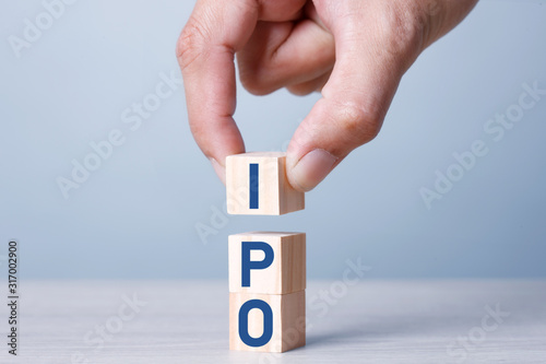 Busiiness Concept IPO Stack of wooden blocks with letters, Initial Public Offering IPO concept, random letters around, Blue tone background