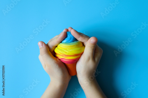 anti stress squishy toy in the form of multicolored ice cream in children's hands on blue background