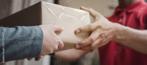 Panoramic banner. delivery service man in red uniform with woman customer receiving parcel post box from courier at home, cargo shipping, express delivery service, online shopping and logistic concept