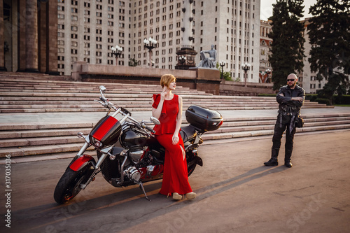 Beautiful unusual couple on a motorcycle against the backdrop of a beautiful stately building in Moscow