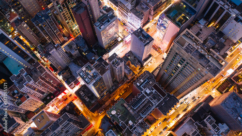 Aerial top view of downtown district buildings in night city light. Bird's eye view from drone of cityscape metropolis infrastructure, crossing streets with parked cars. Development infrastructure