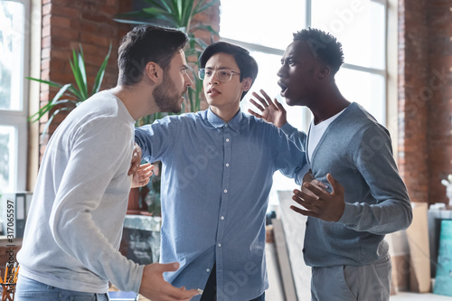 Young angry coworkers having quarrel at office