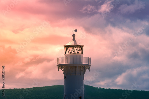 Close up of old white lighthouse tower with epic sunset sky on the background