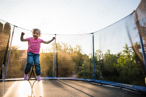 Happy kid playing on trampoline in the backyard