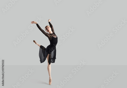 Woman ballet dancer over gray background.