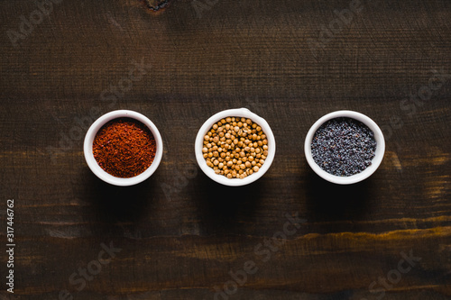 Different kind of spices on dark wooden background. Collection of spices coriander poppy sumac and sesame. Asian or Indian food concept.
