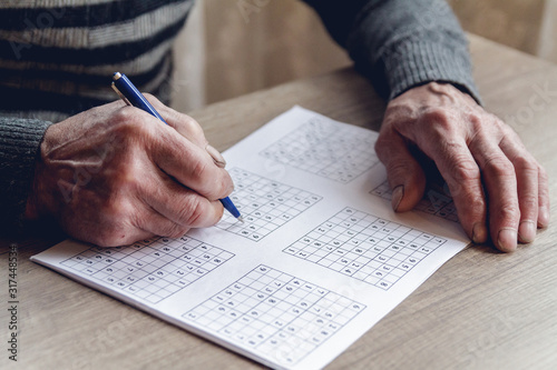 Senior solves sudoku or a crossword puzzle to slow the progressi
