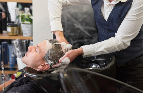 Close up of barber washing man’s hair