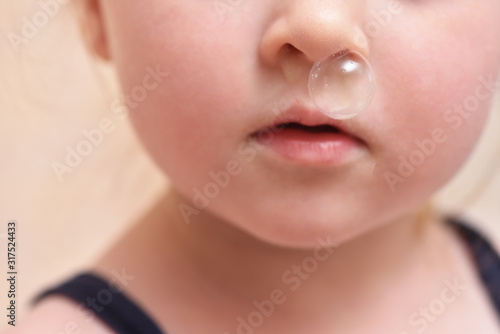Baby girl and big bubble of snot from nose close up.