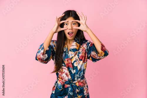 Young asian woman wearing a kimono pajamas keeping eyes opened to find a success opportunity.