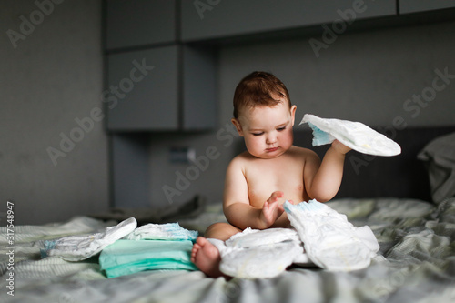 Cute chubby baby sitting with disposable diapers