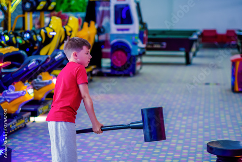 Technology, gaming, entertainment and people concept. Boy playing automatic toy hummer on playground at shopping mall.