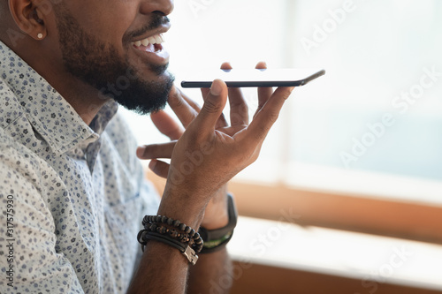 Closeup view african guy talking with friend on speakerphone