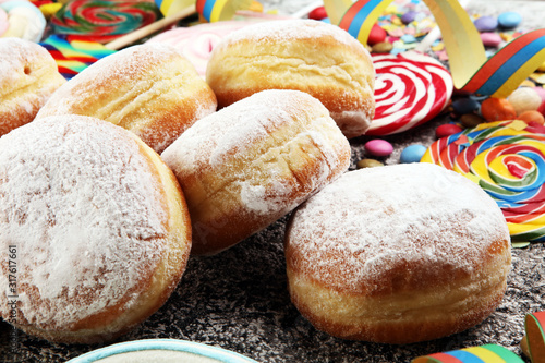 Carnival powdered sugar raised donuts with paper streamers. German berliner or krapfen for carnival