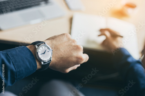 looking at luxury watch on hand check the time at workplace.concept for managing time organization working,punctuality,appointment.fashionable wearing stylish