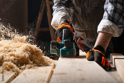 Carpenter works with electrical planer