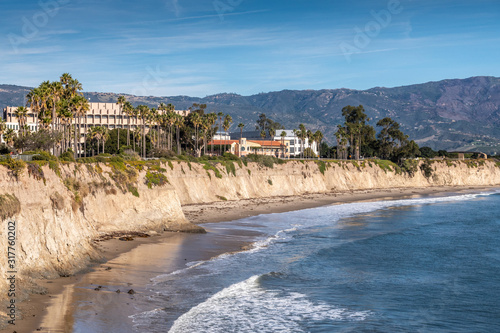 Goleta, CA, USA - January 2, 2020: UCSB, University California Santa Barbara. East side beige cliffs in front of several buildings. Blue ocean in front. Green foliage around. Hills on horizon and blue