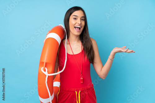 Lifeguard woman over isolated blue background with lifeguard equipment and with shocked facial expression