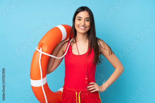 Lifeguard woman over isolated blue background with lifeguard equipment and with happy expression
