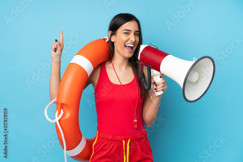 Lifeguard woman over isolated blue background with lifeguard equipment and shouting through a megaphone