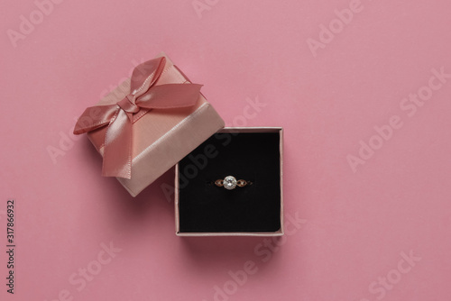 Gift box and engagement gold ring with diamond on pink pastel background. Wedding, romantic concept. Jewelry. Top view. Flat lay