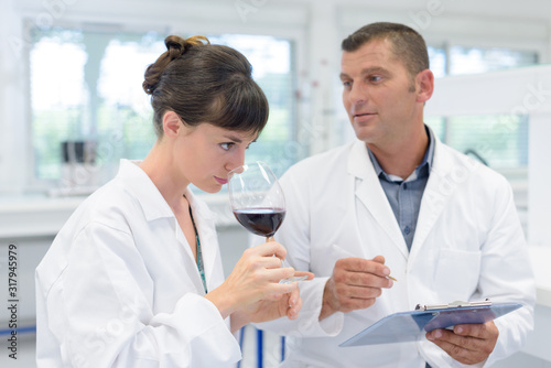 oenologist smelling wine colleague holding clipboard to note findings