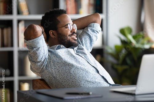 Relaxed calm african businessman resting sit at office desk