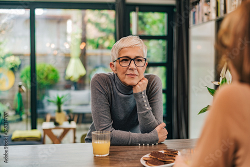 Portrait of attentive modern mature woman listening to a friend at home.