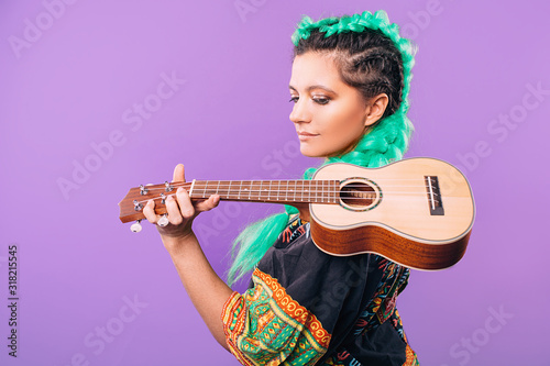 Rastafari woman with ukulele on her shoulder. Musical instrument ukulele. Hawaiian guitar on a violet background