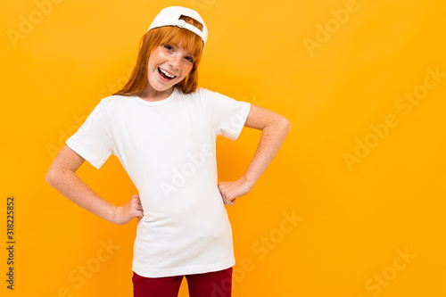 Happy girl with red hair smiles and gesticulates isolated on yellow background