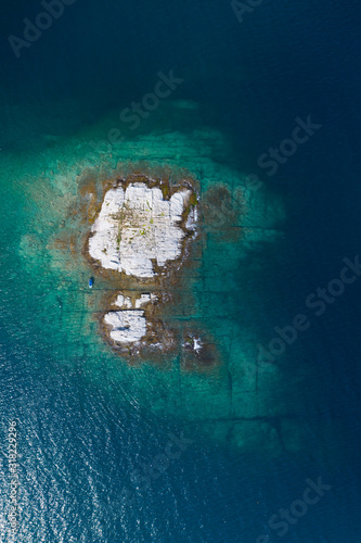 Aerial drone view of a remote rocky island in open sea.