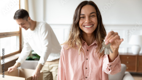 Smiling young wife show keys moving together with spouse