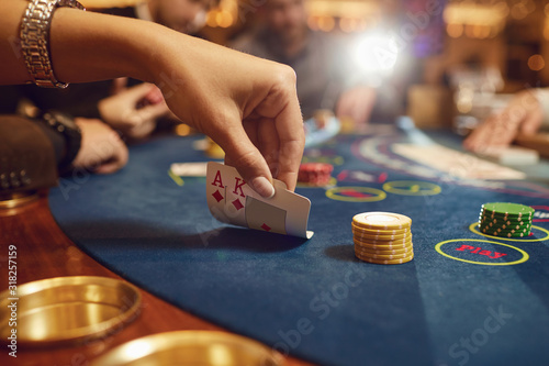 Close-up hands of a poker player checking cards in a casino.