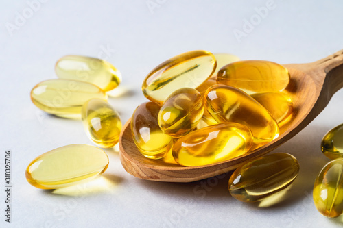 Omega 3 yellow capsules in wooden spoon on white background. EPA and DHA are two types of Omega-3 fats Essential Fatty Acids.