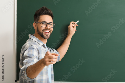 Male teacher writing on blackboard in classroom