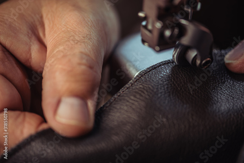 cropped view of cobbler sewing genuine leather on sewing machine