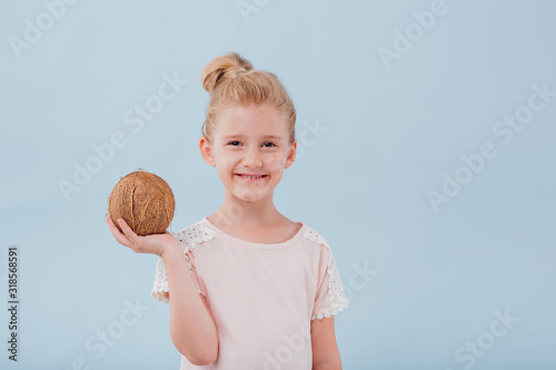 girl with coconut in hand. isolated on blue background, copy space, in studio
