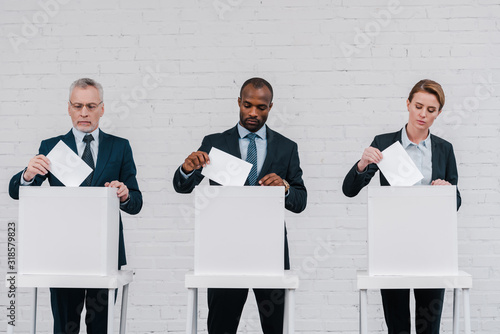 multicultural voters putting ballots in voting boxes