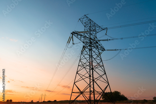 The silhouette of the evening electricity transmission pylon. Power transmission from a power plant to a city.