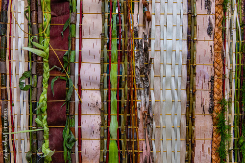 Closeup full frame shot of wooden bamboos and strips decoration with braided leaves representing abstract wampum in event outdoor