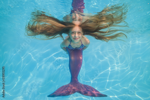 girl in a mermaid costume poses underwater in a pool. Young beautiful girl poses underwater in the pool.